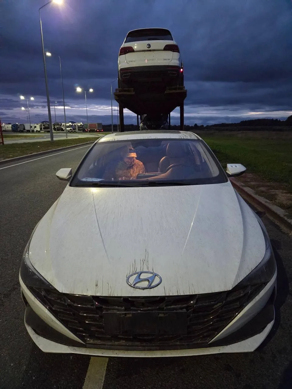 Hyundai Elantra спереди в сумерках рядом с автовозом